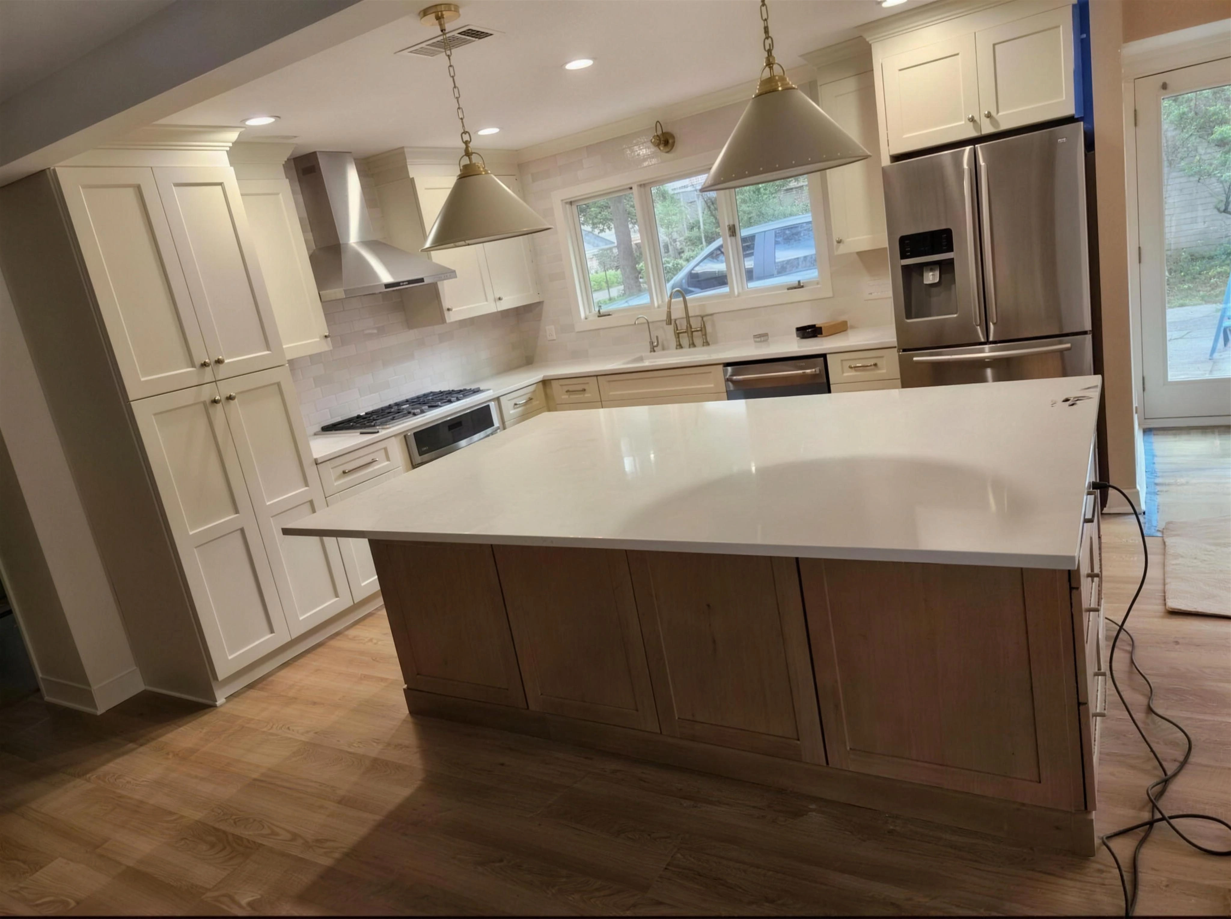 Kitchen with white cabinets, a wood-tone island, pendant lights and stainless steel appliances.